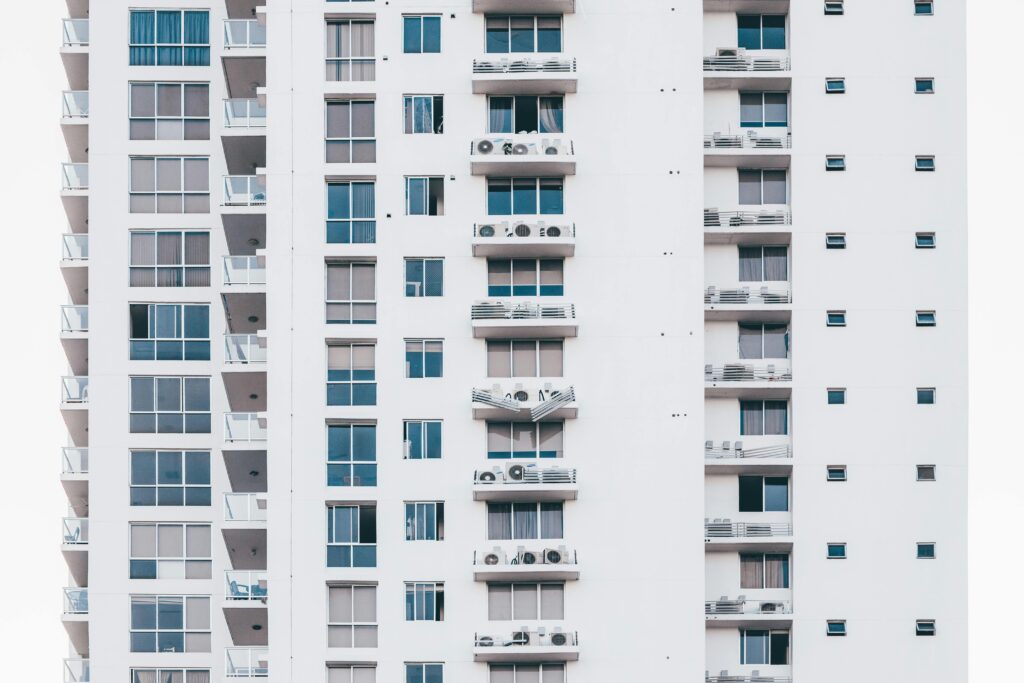 A sleek, modern high-rise building with a glass facade and multiple balconies, showcasing urban architecture.